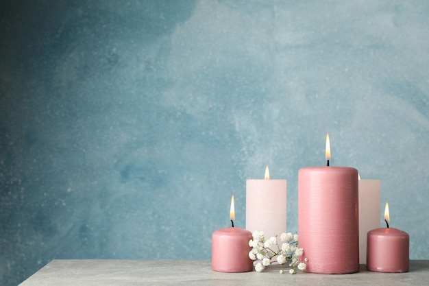 Burning candles and flower against blue, space for text