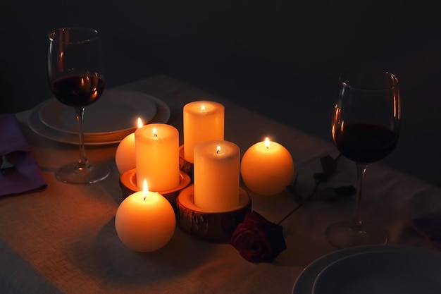 Burning candles and glasses of wine on table in darkness