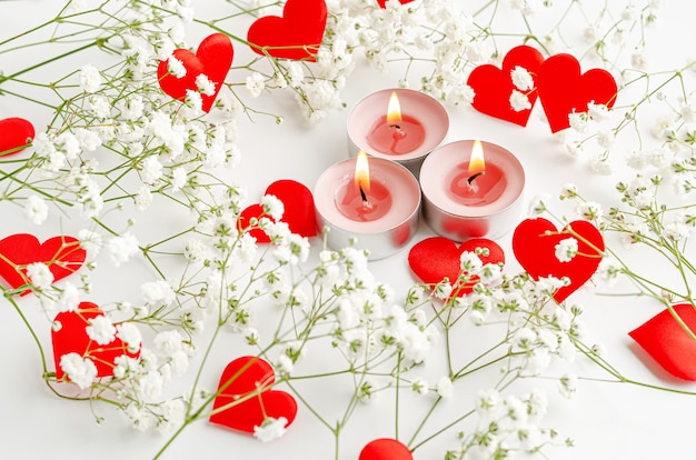 Burning candles and red hearts decorated with flowers