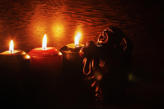 Burning candles and a statue on a black background