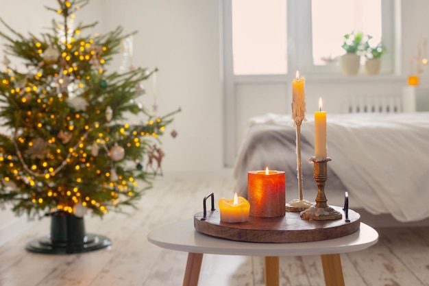 Burning candles on table on background christmas tree at home