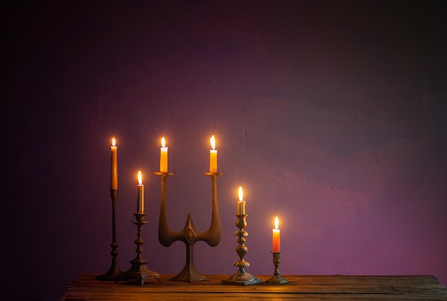 Burning candles in vintage candlesticks on dark background