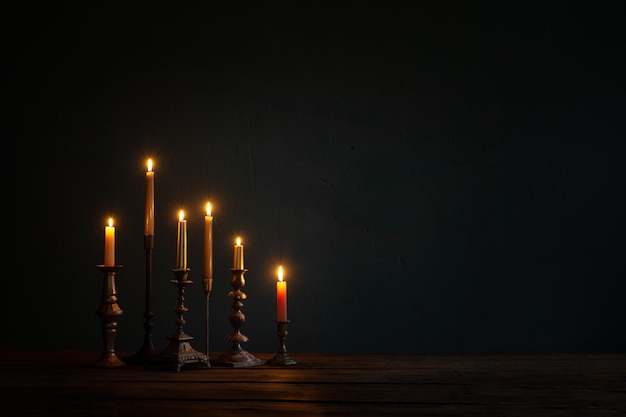 Burning candles in vintage candlesticks on dark background