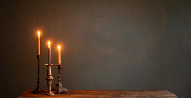 Burning candles in vintage candlesticks on dark background