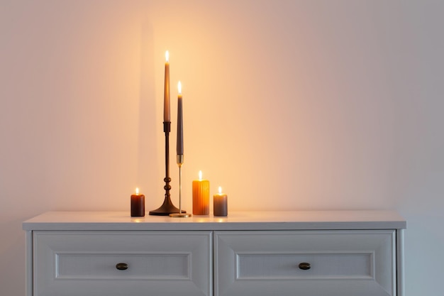 Burning candles on white wooden shelf in white interior