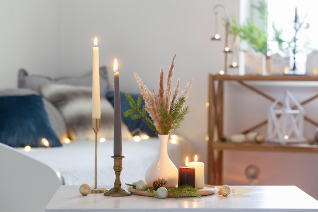 Burning candles with christmas decor in white cozy interior