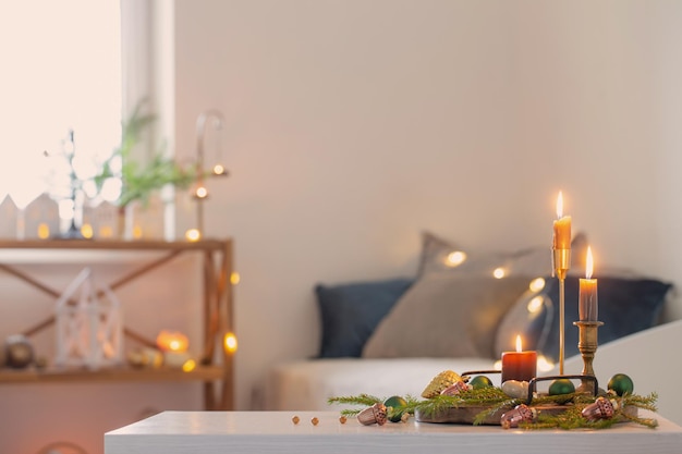 Burning candles with christmas decor in white cozy interior