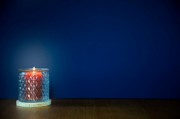 Burning candles on wooden table against dark blue background with copy space stylish home decoration