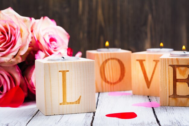 burning candles and word Love made of wooden candle holders