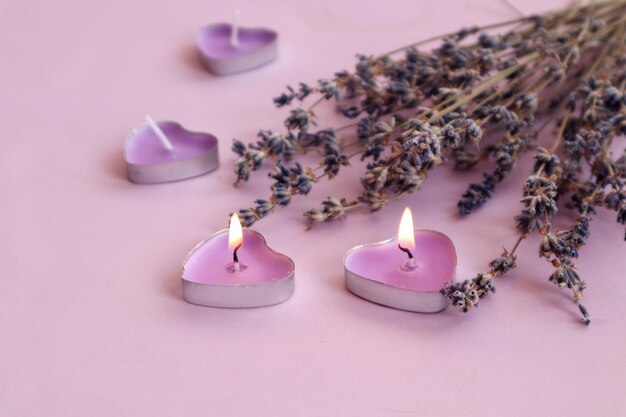 Burning candleshearts with a bouquet of lavender on a pastel background a place for text