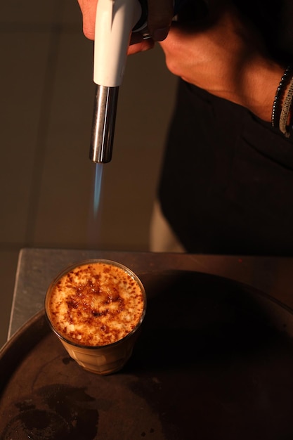 Burning Crème brûlée with a blowtorch. Burnt sugar on vanilla cream surface.