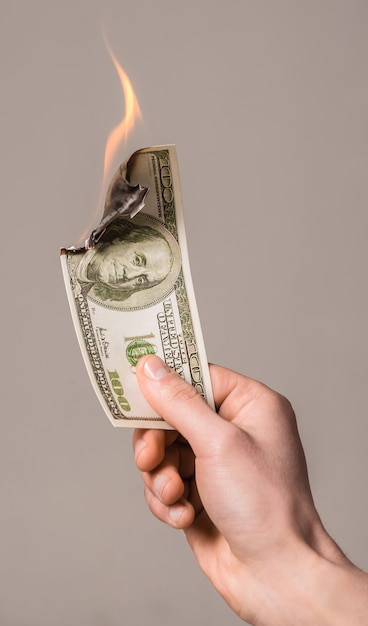 Burning dollar in hand isolated on grey