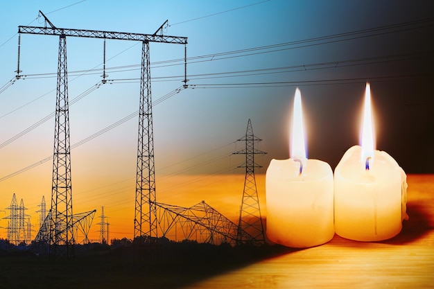 Burning flame candle and power lines on background Energy outage and blackout Energy crisis Price increase of electricity for home and industry