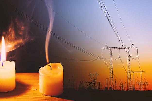 Burning flame and extinguished candle and power lines on background Energy outage and blackout Energy crisis Price increase of electricity for home and industry