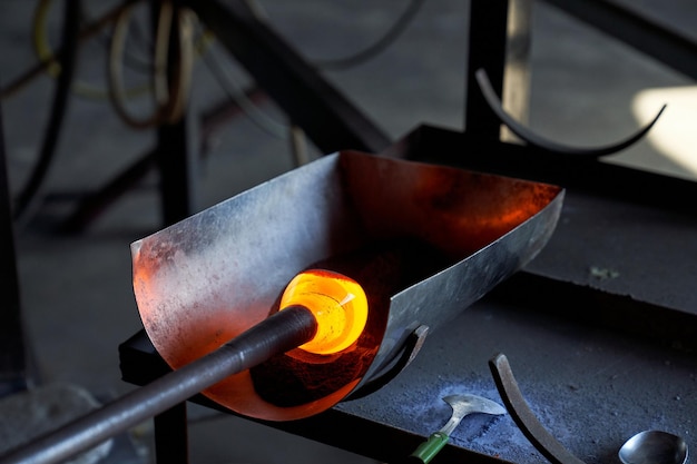 Burning hot liquid glass mass on blowpipe in process of producing glass base