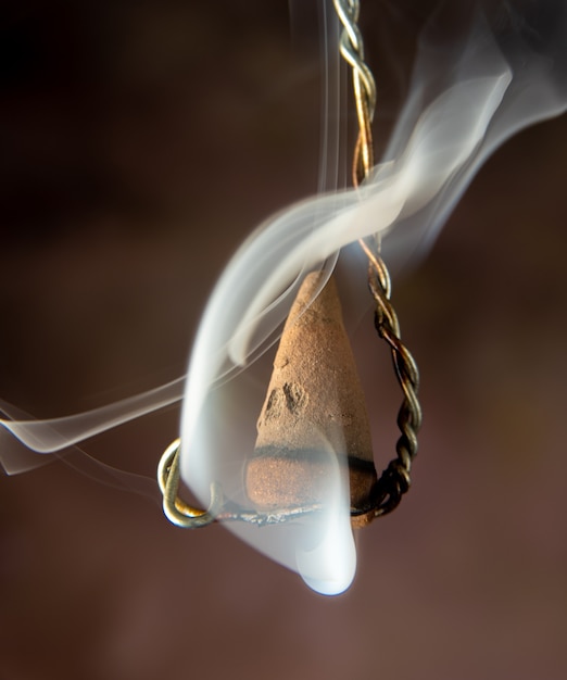 Burning incense hanging on an old wire, selective focus.