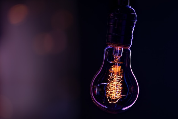 A burning lamp hangs in the dark on a blurred background close up.