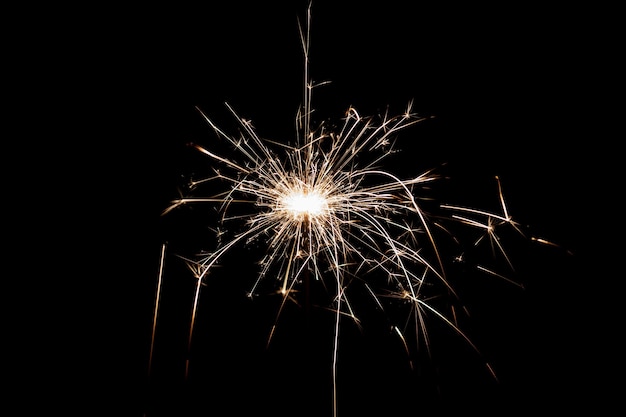 Burning sparkler isolated on black background Fireworks theme Light effect and texture