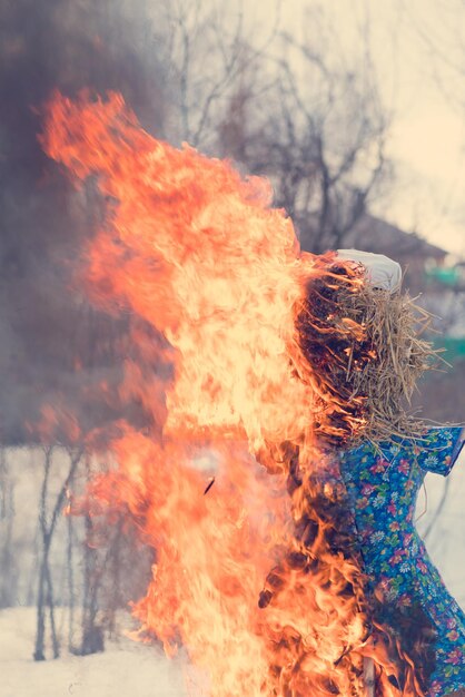 Burning stuffed Maslenitsa on the background of white snow and trees