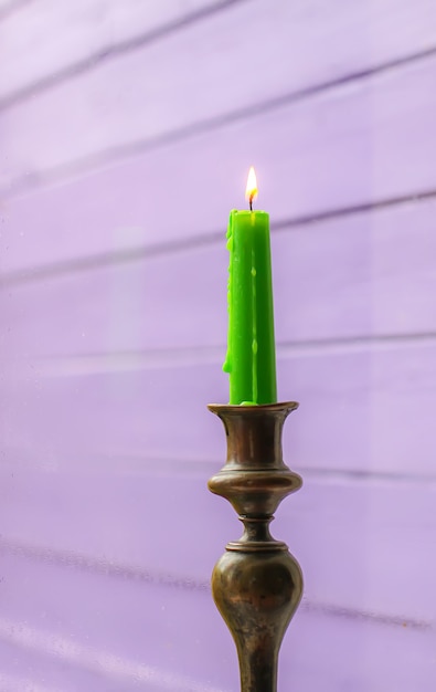 Burning wax candle in brass candlestick in country house interior.