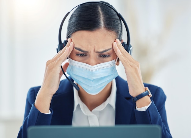 Burnout headache and pain call center agent working on laptop headset and medical face mask Tired stress and frustrated customer service or contact us woman working on computer with 404 error