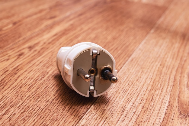 Burnt electrical plug on a wooden background