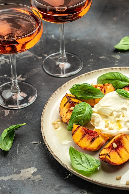 Burrata cheese and grilled peaches with rose wine vertical image top view place for text