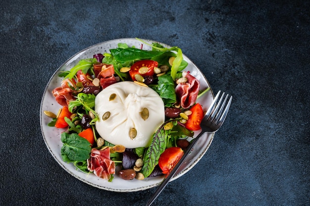 Burrata Italian fresh cheese made from cream and milk of buffalo or cow Burrata salad with tomatoes and salad mix Healthy eating concept Keto diet salad