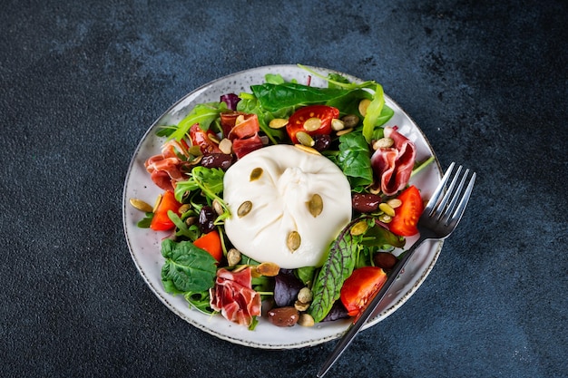 Burrata Italian fresh cheese made from cream and milk of buffalo or cow Burrata salad with tomatoes and salad mix Healthy eating concept Keto diet salad