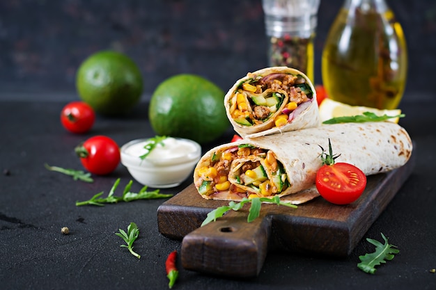 Burritos wraps with beef and vegetables on  black background. Beef burrito, mexican food.