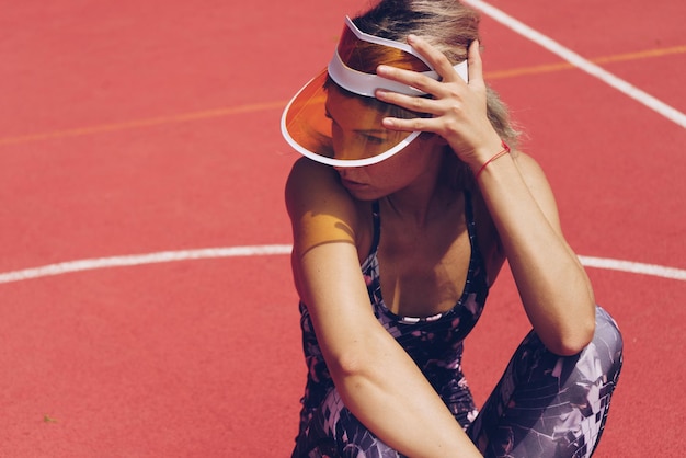 Burying her face in her shoulder in chagrin a sports girl sits on the court