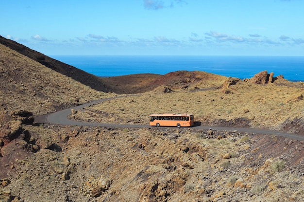 Bus on the road of volcanic landscape in Lanzarote Canary Islands Spain