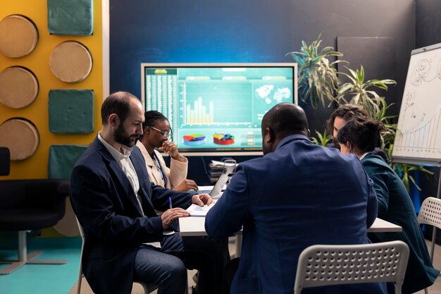 Photo business affiliates reviewing sales infographics in a conference room