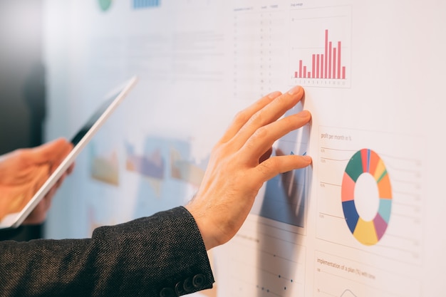 Business analyst studying company growth rates. Closeup of male hands pointing at graphs on whiteboard.