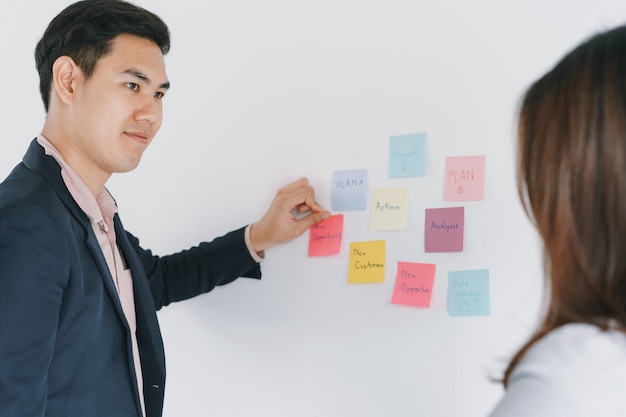 Business Asian two people meeting in the office and using post it notes to share the idea