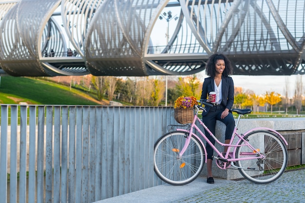 Business black woman with vintage bicycle drinking coffe