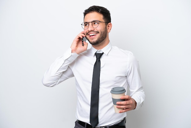 Business Brazilian man isolated on white background holding coffee to take away and a mobile