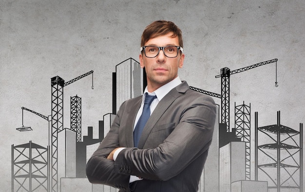 business, building and office concept - attractive businessman or teacher in glasses with construction site on the back