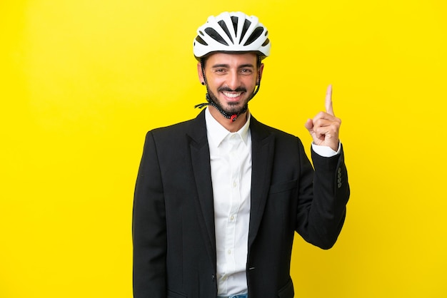 Business caucasian man with a bike helmet isolated on yellow background showing and lifting a finger in sign of the best