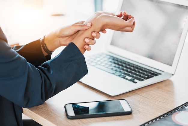 Business closeup and woman with wrist pain burnout and laptop in office stress and deadline Zoom female employee and professional with smartphone injury and muscle strain in workplace and hand