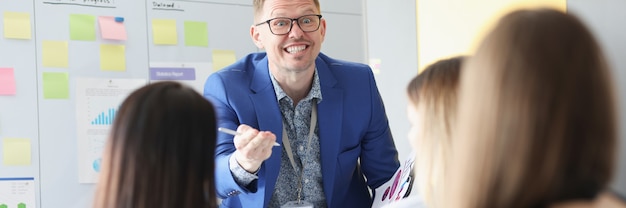 Business coach with glasses explaining information to listeners in audience