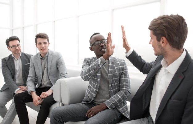 Business colleagues giving each other a high five while sitting in the office lobbyphoto with copy space