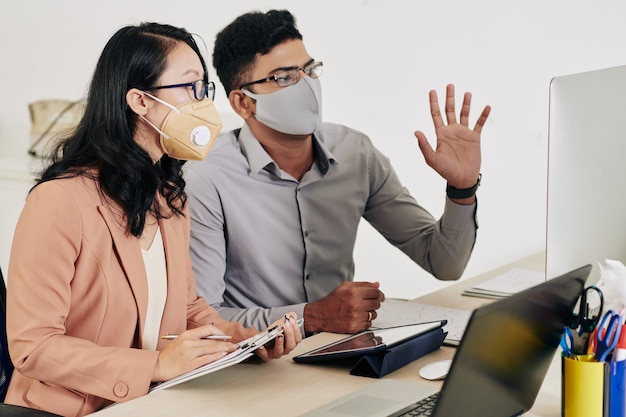 Business colleagues in protective masks having online conference with colleagues from other countries