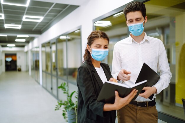 Photo business colleagues wearing medical face mask discussing together work issues at office. teamwork during pandemic in quarantine city. covid-19.