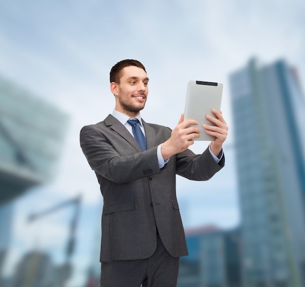 business, communication, modern technology and office concept - smiling buisnessman with tablet pc computer