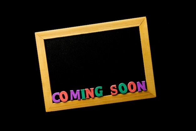 Photo business concept - blackboard with inscription coming soon on a black table.