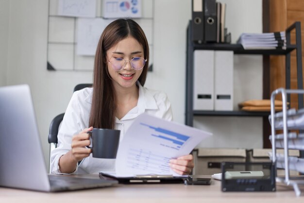 Business concept Businesswoman is drinking coffee while reading business document in office