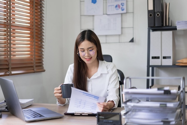 Business concept Businesswoman is drinking coffee while reading business document in office