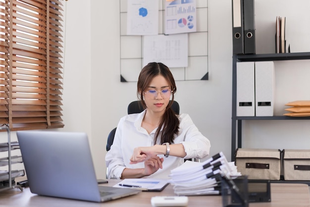 Business concept Businesswoman is look at the time on the wristwatch after working hard in office