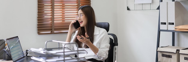 Business concept Businesswoman is talking financial data with partner on smartphone at office